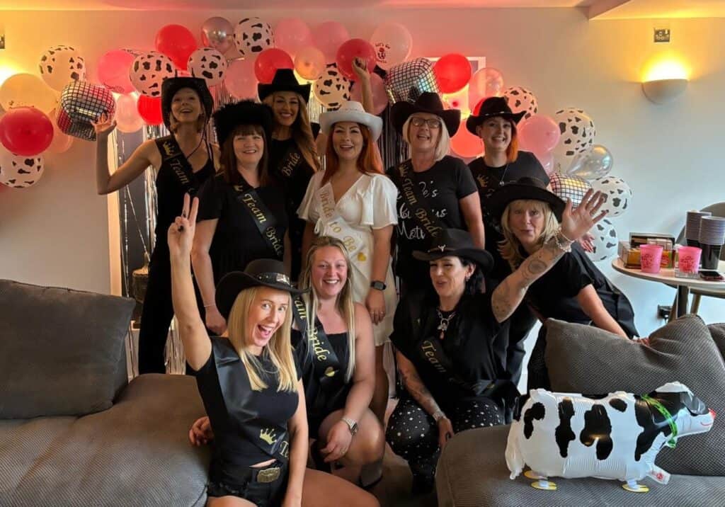 Bride-to-be enjoying a line dancing hen party, dressed in a chic cowgirl hat, striking a fun pose while learning sassy dance moves. The perfect line dancing hen do experience for a stylish, Instagram-worthy celebration!